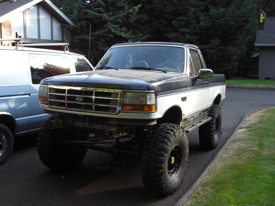1993 Ford Bronco, two-tone black and white, lifted with large tires, front 3/4 view