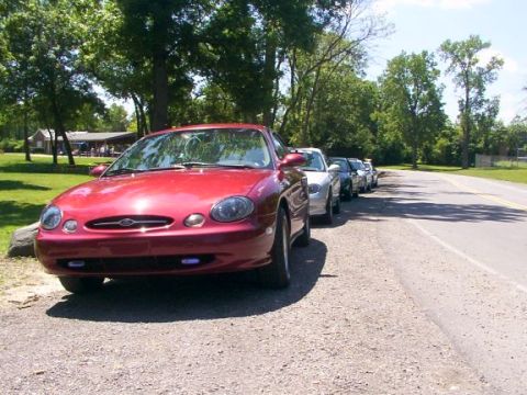 1998 Ford Taurus - Line of cars parked on the side of the road, with a red 1998 Ford Taurus in the foreground.