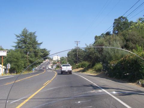 1994 Ford F-150 - A white pickup truck travels down a rural road on a clear day, with other vehicles visible in the distance.