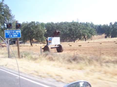 1994 Ford F-150 - A roadside sculpture stands in a field next to a traffic information sign.