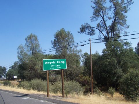 1994 Ford F-150 - A green sign marks the city limit for Angels Camp, with trees and a clear blue sky overhead.