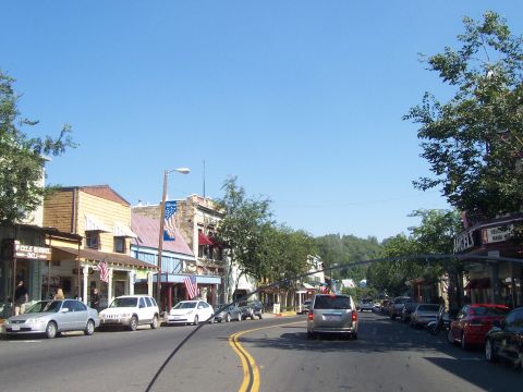 1994 Ford F-150 - A street lined with shops and parked vehicles under a bright blue sky.
