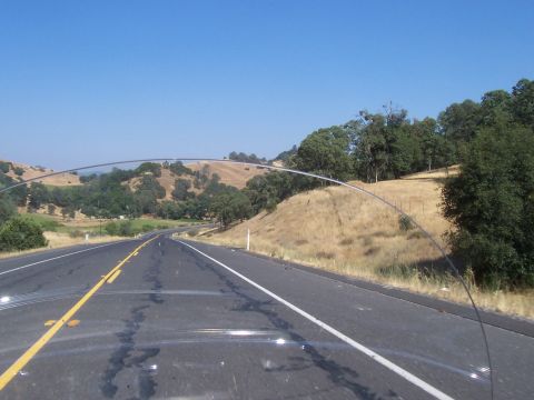1994 Ford F-150 - A scenic drive along a highway, with dry grass-covered hills and scattered trees under a bright blue sky.