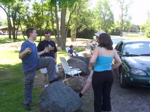 1998 Ford Taurus - A green sedan is parked on a gravel surface, with several people gathered around it outdoors.