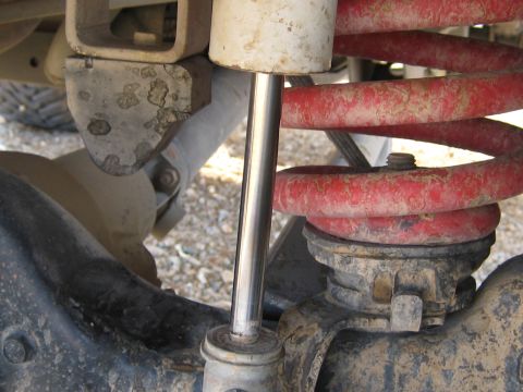 1996 Ford Bronco - Close-up view of a vehicle's rear suspension system, highlighting the red coil spring and shock absorber.