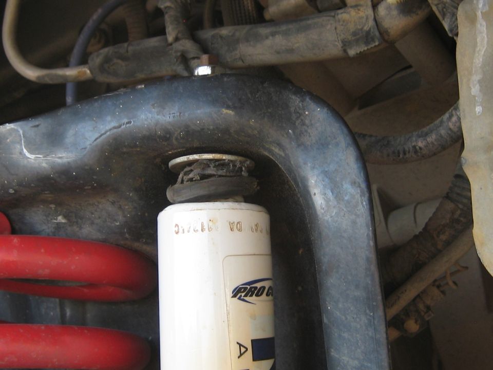 close-up of a white shock absorber with 'Pro Comp' logo and red coil spring