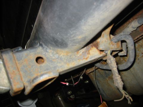 1995 Ford Bronco - Undercarriage view of a vehicle's rusty frame and exposed wiring.