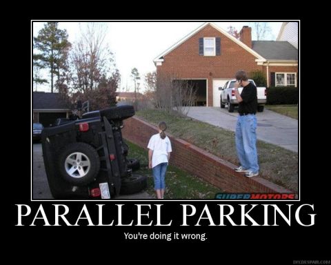 1987 Ford Bronco - This is not how you parallel park. A black Jeep Wrangler is on its side next to a brick wall, with two onlookers.