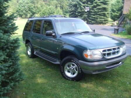 1996 Ford Bronco - This green SUV, likely a 1995 model, is parked on a grassy lawn with trees in the background.
