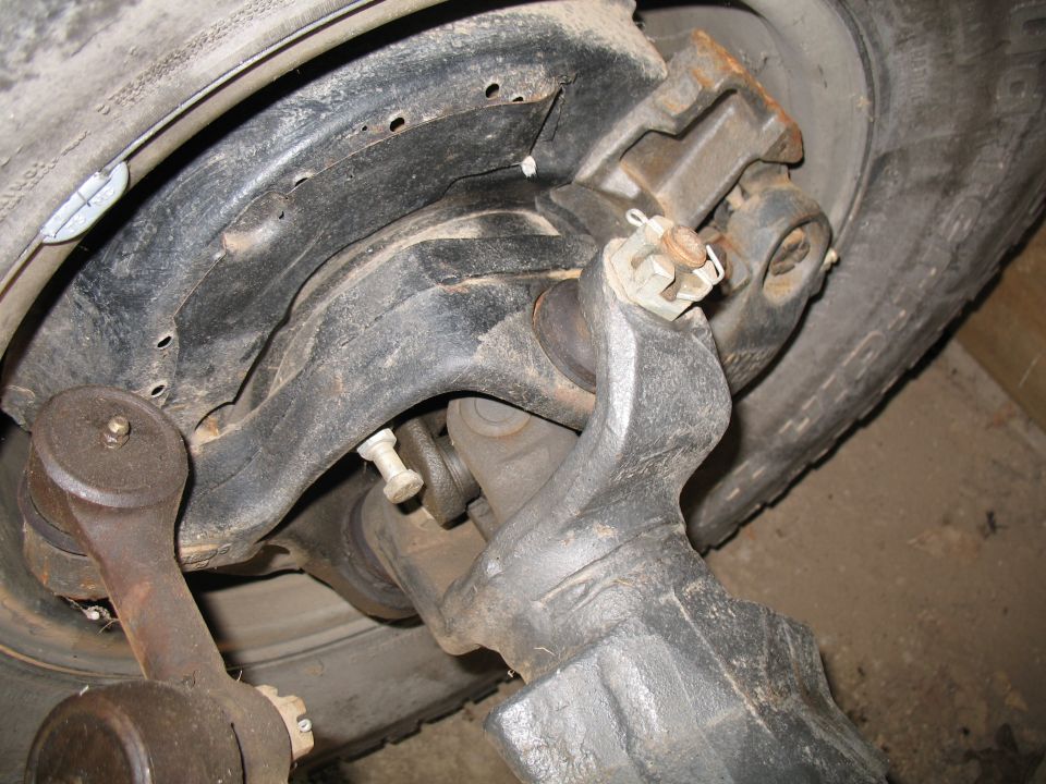 Underside view of a vehicle rear axle, backing plate, and tire