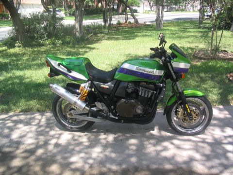 1981 Kawasaki Bayou - A green and purple Kawasaki motorcycle is parked outdoors on a sunny day.