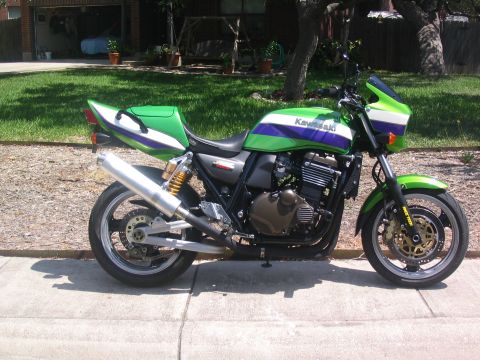 1981 Kawasaki Bayou - A Kawasaki motorcycle with a green, purple, and white paint scheme is parked outdoors on a sunny day.