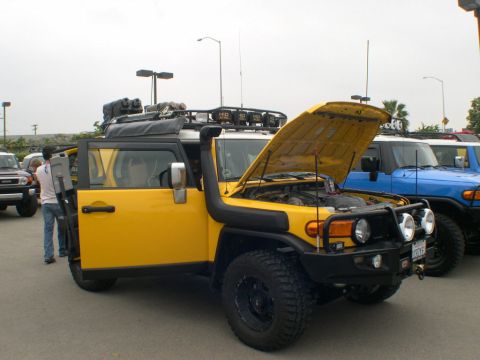2007 Toyota FJ Cruiser - Yellow 2007 Toyota FJ Cruiser parked with its hood open, alongside a blue FJ Cruiser.