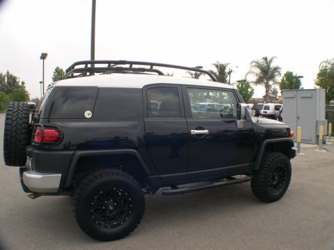 2007 Toyota FJ Cruiser - A black Toyota FJ Cruiser is parked outdoors, showing its side profile and rear-mounted spare tire.