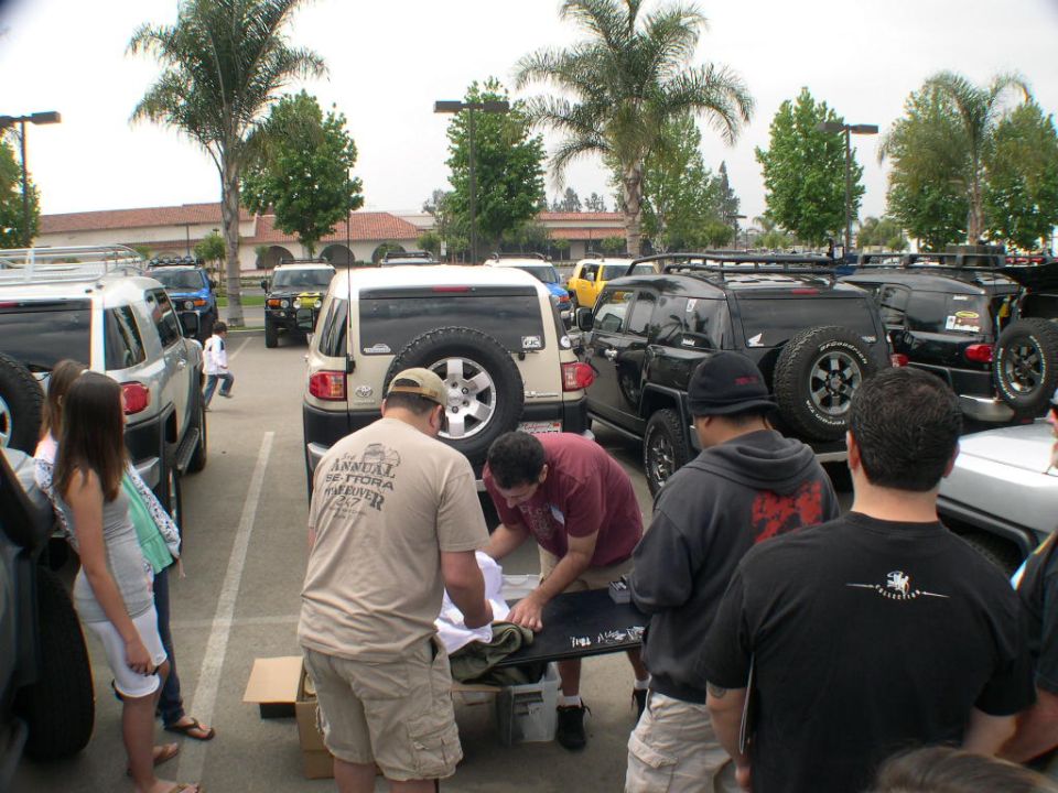 People gathered around a table with Toyota FJ Cruisers parked behind them.