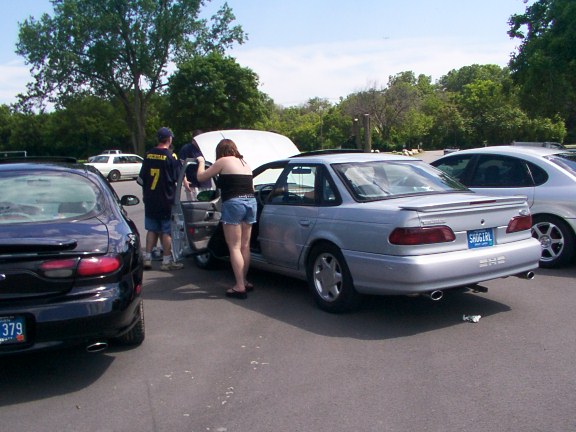 Silver sedan with a spoiler and a blue license plate, viewed from the rear