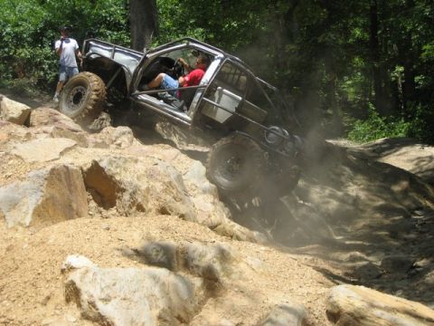 1995 Ford Bronco - An off-road vehicle navigates a challenging rocky terrain, with a person watching from the side.