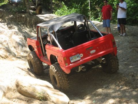1995 Ford Bronco - This modified Bronco is navigating a challenging off-road course with steep inclines and rocky terrain.