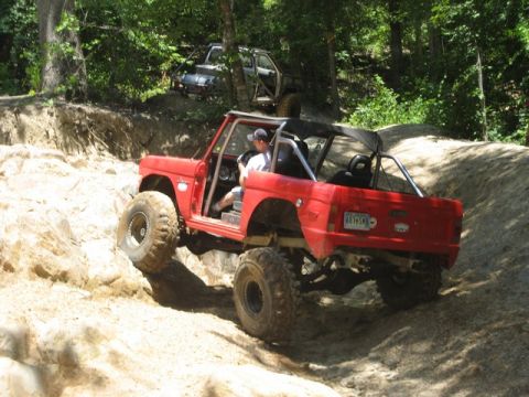 1995 Ford Bronco - Modified red Bronco navigating a steep, rocky trail with another vehicle following.