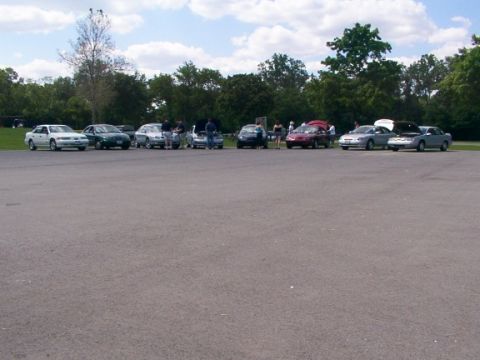 1998 Ford Taurus - A group of cars are parked in a lot during an outdoor event.