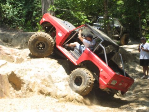 1995 Ford Bronco - A red off-road vehicle navigates a steep, rocky incline during an outdoor excursion.