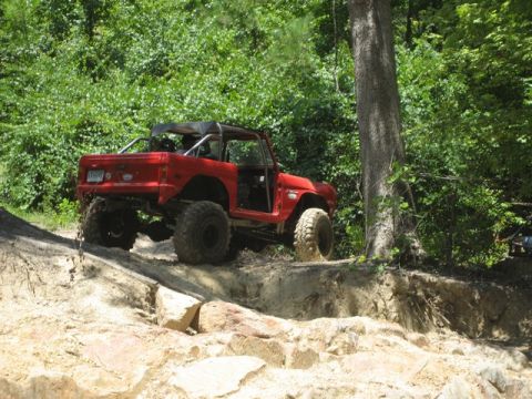 1995 Ford Bronco - This red Ford Bronco, likely from the 1970s, navigates a challenging off-road course.