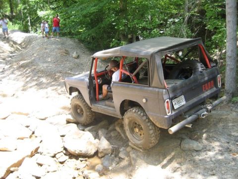 1995 Ford Bronco - This classic Ford Bronco navigates a rocky off-road trail with spectators observing from the side.