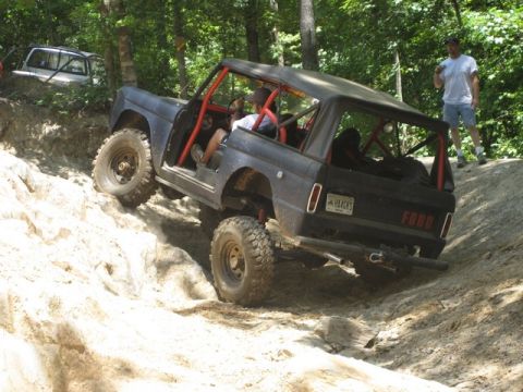 1995 Ford Bronco - A modified Ford Bronco navigates a challenging off-road trail with a second vehicle in the background.