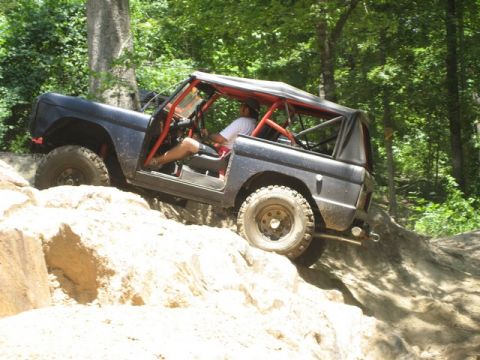 1995 Ford Bronco - This modified SUV navigates a challenging off-road course, demonstrating its capability on rough terrain.
