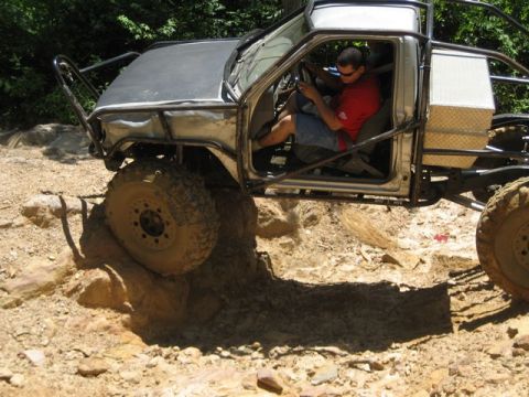 1995 Ford Bronco - A heavily modified off-road vehicle navigates a challenging rocky trail.
