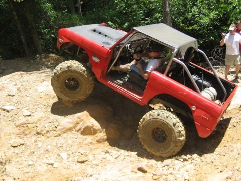 1995 Ford Bronco - Off-road SUV navigates a steep, rocky incline on a sunny day.