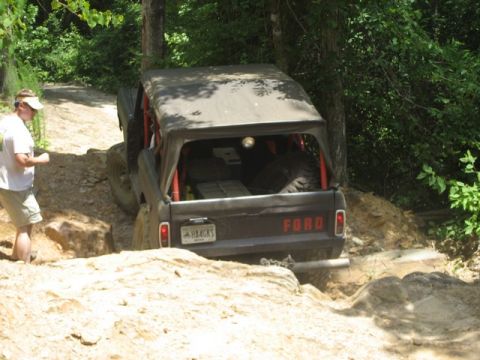 1995 Ford Bronco - A Ford Bronco navigates a challenging off-road course with a person watching from the side.