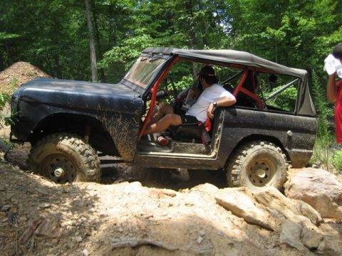 1995 Ford Bronco - First-generation Ford Bronco navigating a challenging off-road trail with a driver inside.