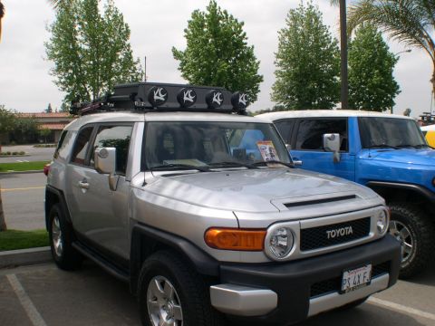 2007 Toyota FJ Cruiser - Two Toyota FJ Cruisers, one silver and one blue, are parked side-by-side at an outdoor event.