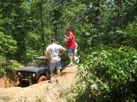 1995 Ford Bronco - Ford Bronco navigating a steep, muddy off-road trail with onlookers.