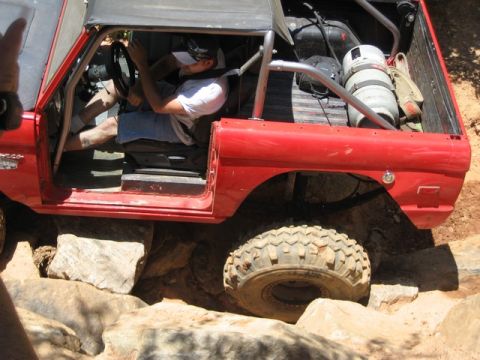 1995 Ford Bronco - This red Ford Bronco is navigating a rocky trail, demonstrating its off-road capabilities.