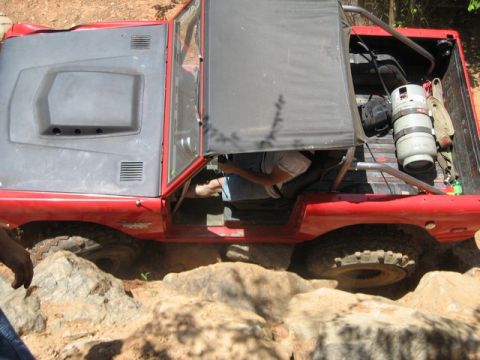 1995 Ford Bronco - Off-road vehicle navigating rocky terrain with a propane tank secured in the rear.