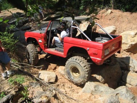 1995 Ford Bronco - A red 1978 Ford Bronco navigates a challenging rocky terrain during an off-road excursion.