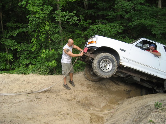 White 1995 Ford Bronco stuck on a dirt hill, guy winching it out