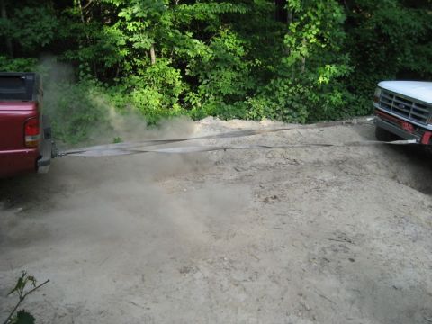 1995 Ford Bronco - Two trucks are stuck in the dirt, with one pulling the other using tow straps and kicking up dust.