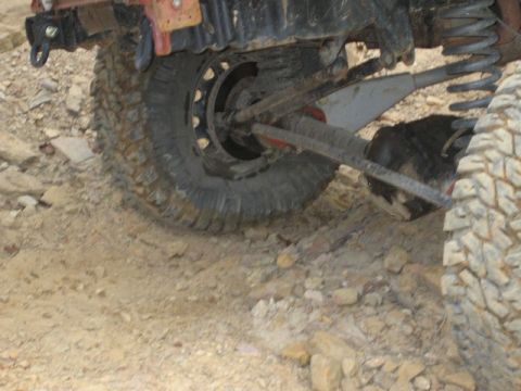 1995 Ford Bronco - Close-up of the rear axle and suspension of an off-road vehicle on a rocky trail.
