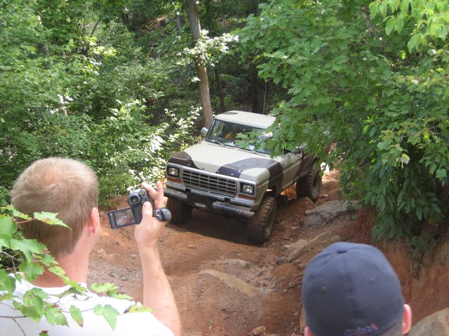 Ford F-Series pickup truck on a dirt trail, with two people filming it
