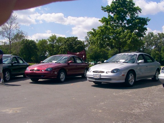 1998 Ford Taurus sedan parked next to another red sedan and a dark green sedan