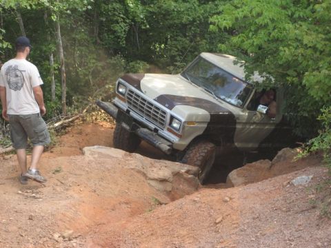 1995 Ford Bronco - A man watches a Ford F-Series truck crawl over rocks on a dirt path.