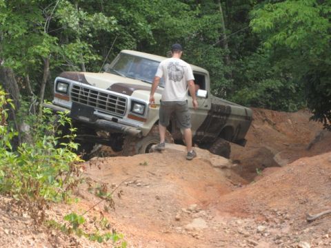 1995 Ford Bronco - Ford F-Series pickup truck is shown off-roading on a challenging dirt path.