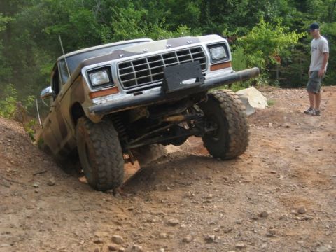 1995 Ford Bronco - A Ford F-Series truck navigates a challenging off-road course with a person observing.
