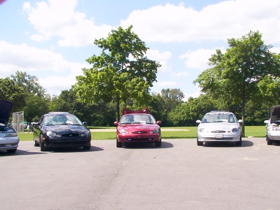 Three Ford Tauruses parked in a lot, one red, one black, and one silver