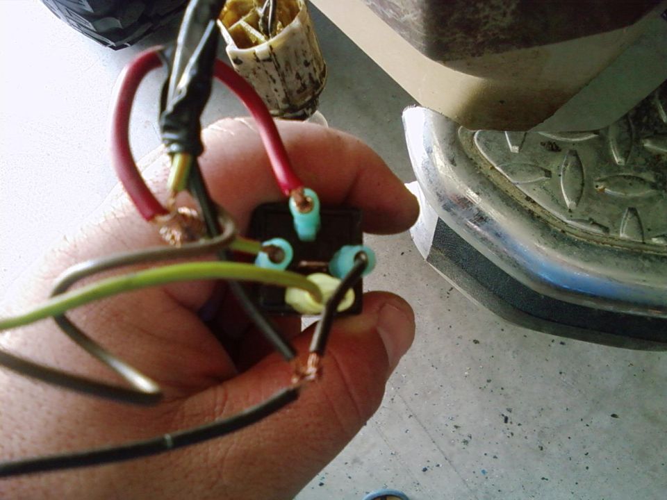 Close-up of wiring harness connected to a black component, with part of a chrome bumper visible
