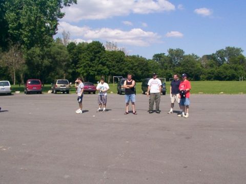 1998 Ford Taurus - A group of people gathered in a parking lot with several vehicles visible in the background.