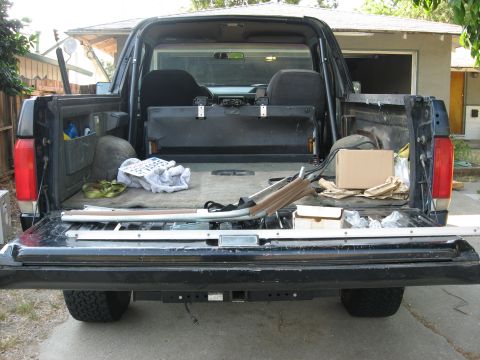 1989 Ford Bronco - Rear view of a black Ford Bronco with its tailgate down, revealing the cargo area and interior.